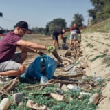 Volunteers clear debris along a riverbank for community recovery